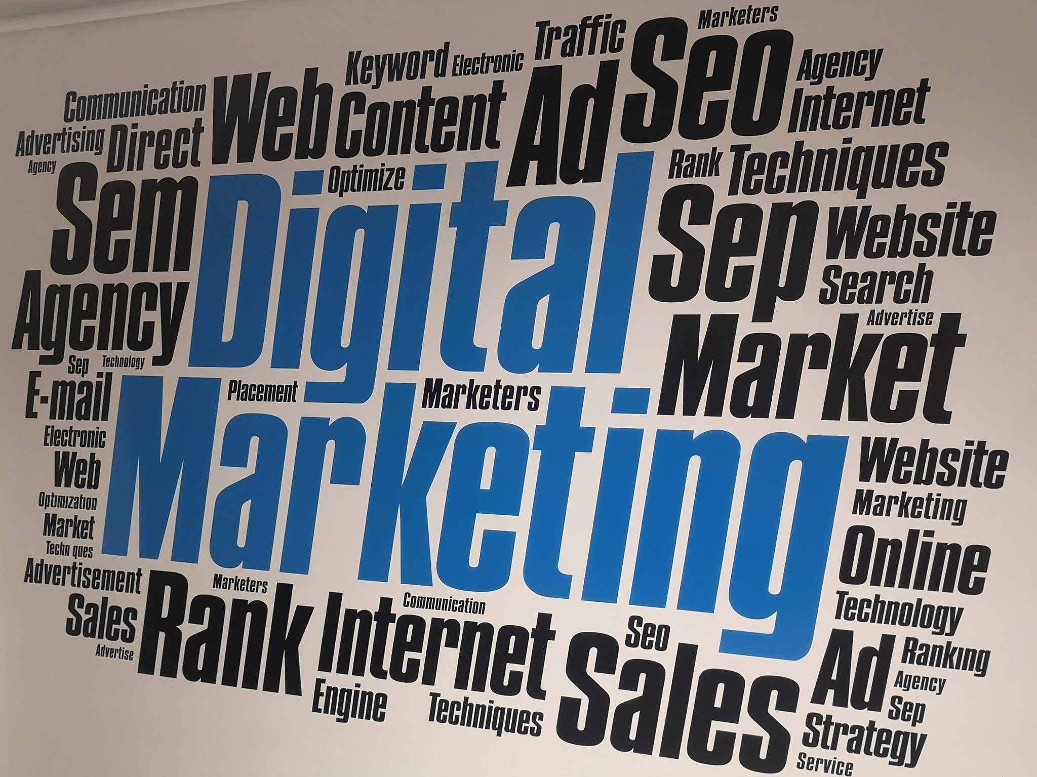 Word cloud z hasłami związanymi z marketingiem internetowym, w tym 'Digital Marketing', 'SEO', 'Web Content', 'Ad', 'Website', 'Internet' w kolorach czarnym i niebieskim na białym tle.