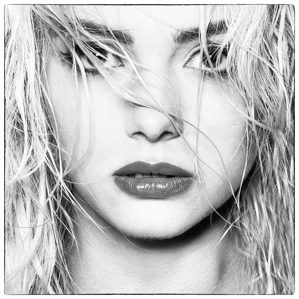 Czarno-biały portret kobiety z mokrymi, blond włosami opadającymi na twarz i jaskrawoczerwonymi ustami.