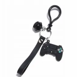 Czarny brelok z zawieszką w kształcie kontrolera do gier, z czarnym paskiem i małą czarną kulką, zawieszony na metalowym kółku i karabińczyku na jasnym tle.