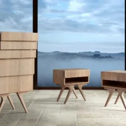 Komplet drewnianych mebli: wysoka komoda z wysuwanymi szufladami i dwie szafki nocne, wszystkie na charakterystycznych, smukłych nóżkach w kształcie litery V, na tle panoramicznego okna z widokiem...