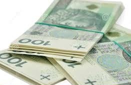 Stosy banknotów 100 zł spięte gumką recepturką, rozłożone na białym tle, widoczne numery seryjne i nominały.