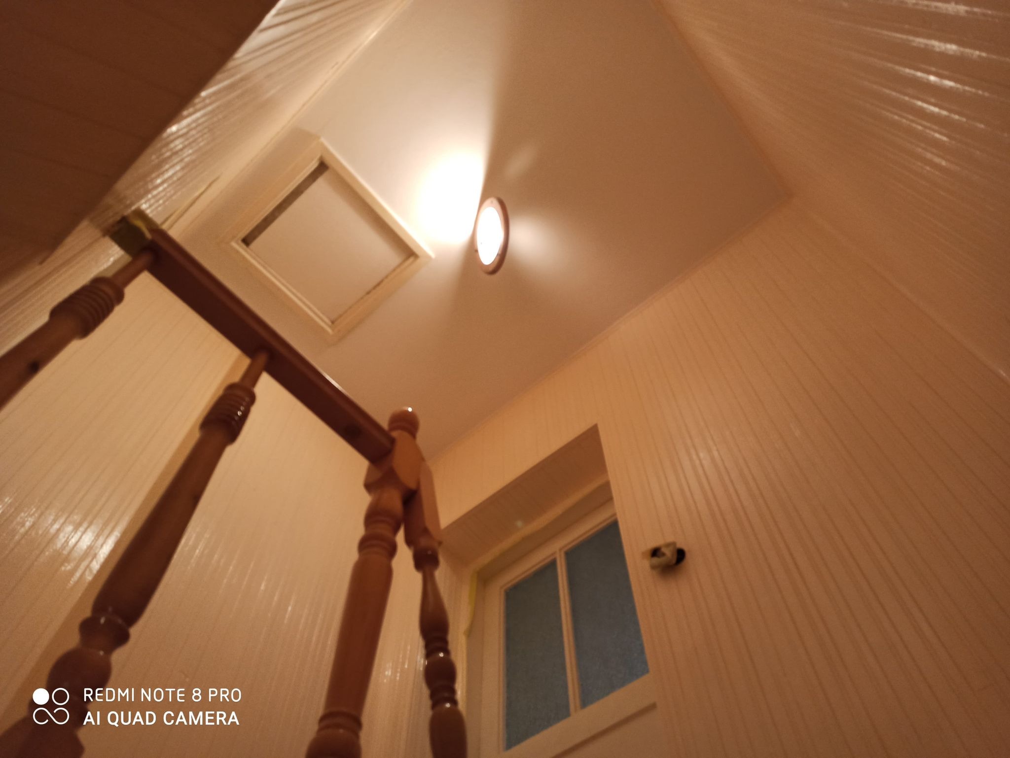 Widok z dołu na drewniane schody z balustradą w domu w Leżajsku, z widocznym fragmentem okna i sufitem z oświetleniem punktowym.