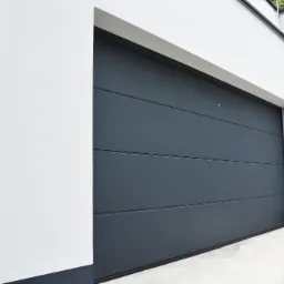 Nowoczesna, segmentowa brama garażowa w kolorze grafitowym, z poziomymi przetłoczeniami, zamontowana w białym budynku z minimalistycznym wykończeniem.