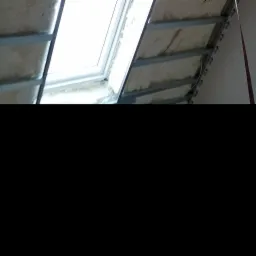 Montaż okna dachowego z izolacją z pianki i metalowym stelażem, widoczne płyty kartonowo-gipsowe marki Regips