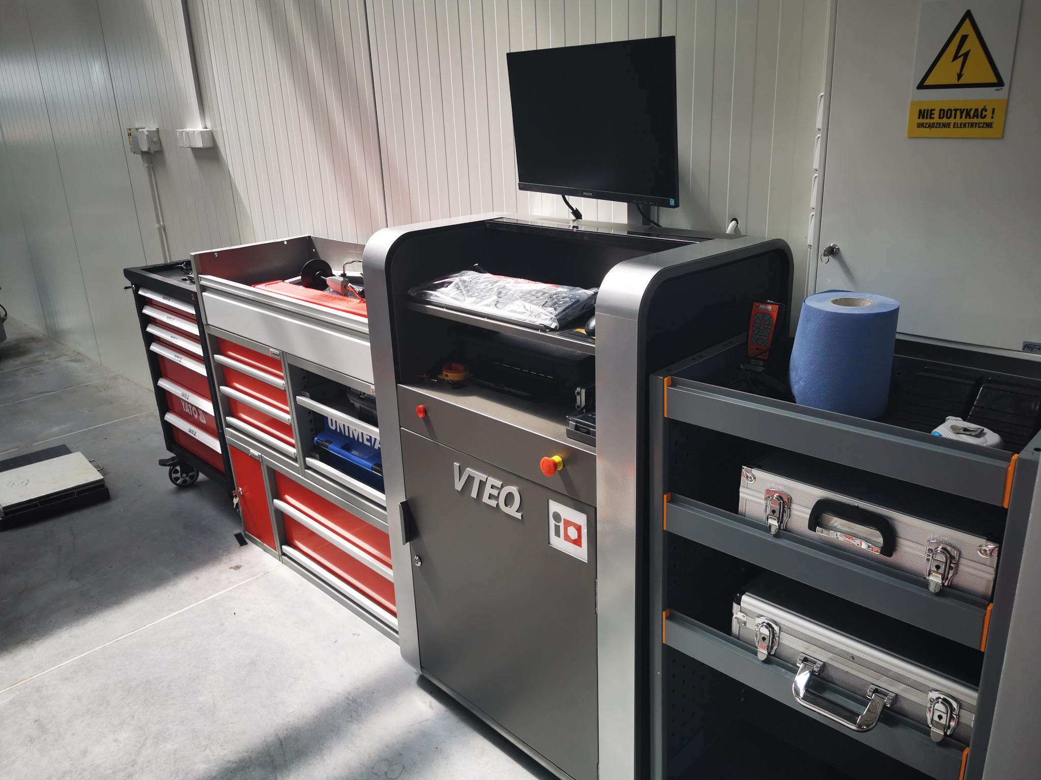 Stanowisko diagnostyczne VTEQ z monitorem, klawiaturą w folii, wózkiem narzędziowym Yato z czerwonymi szufladami i wózkiem z aluminiowymi walizkami w sterylnym warsztacie.