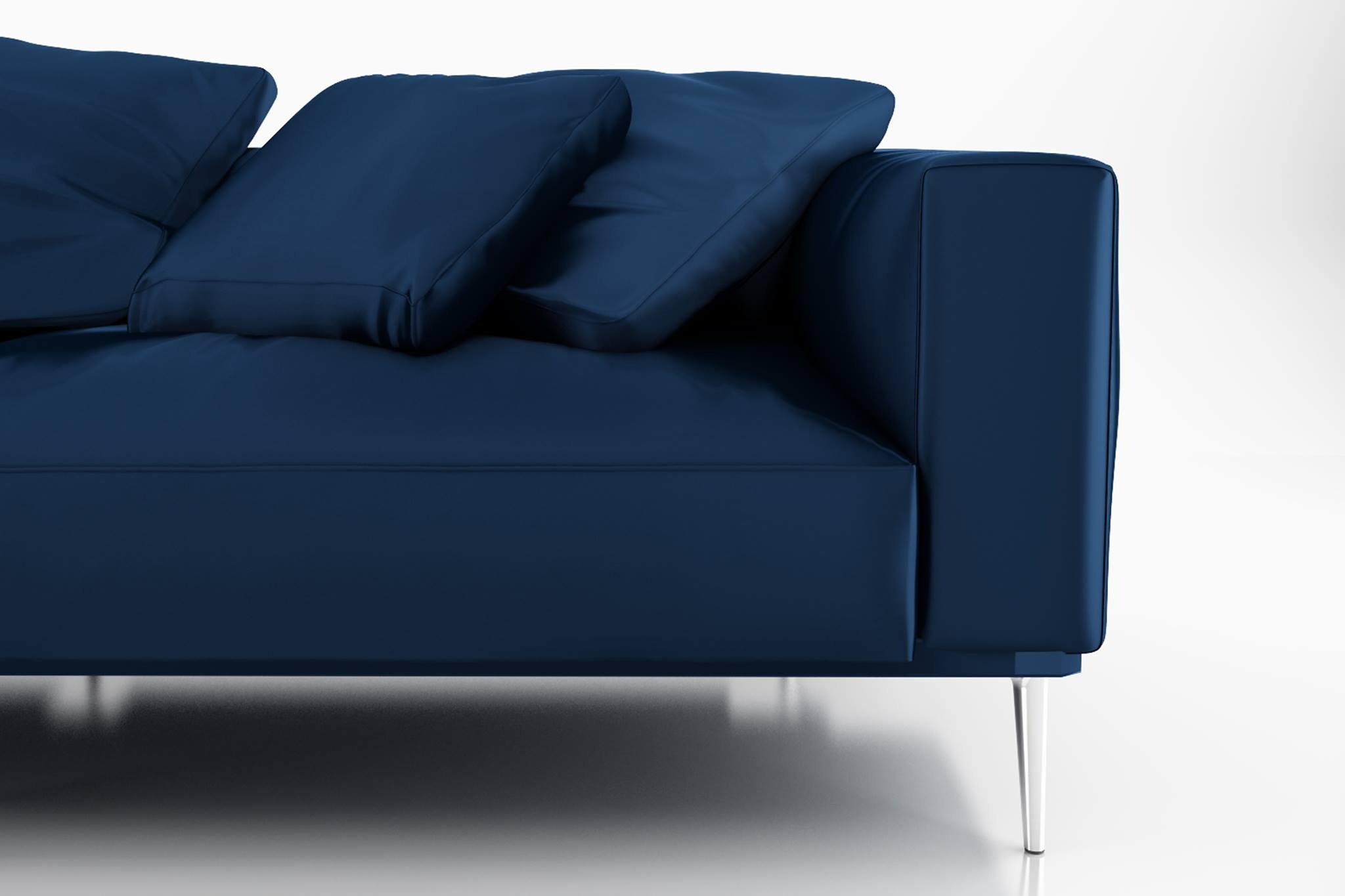 Fragment granatowej sofy z poduszkami i chromowanymi nóżkami, na białym tle, prezentacja mebla w Olsztynie.