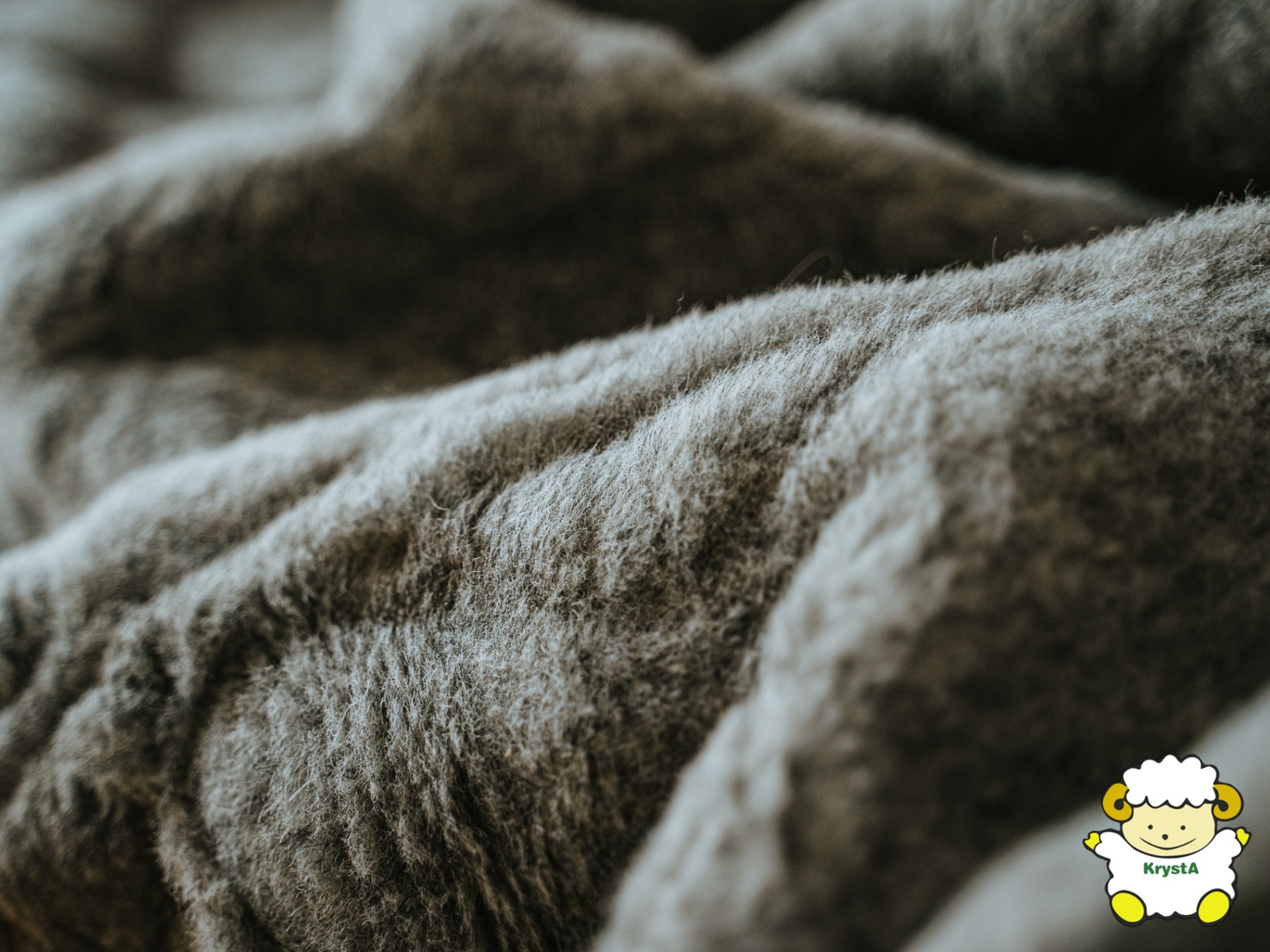 Szczegółowe ujęcie szarej, miękkiej tkaniny pościelowej z logo firmy z Bielska-Białej w prawym dolnym rogu.