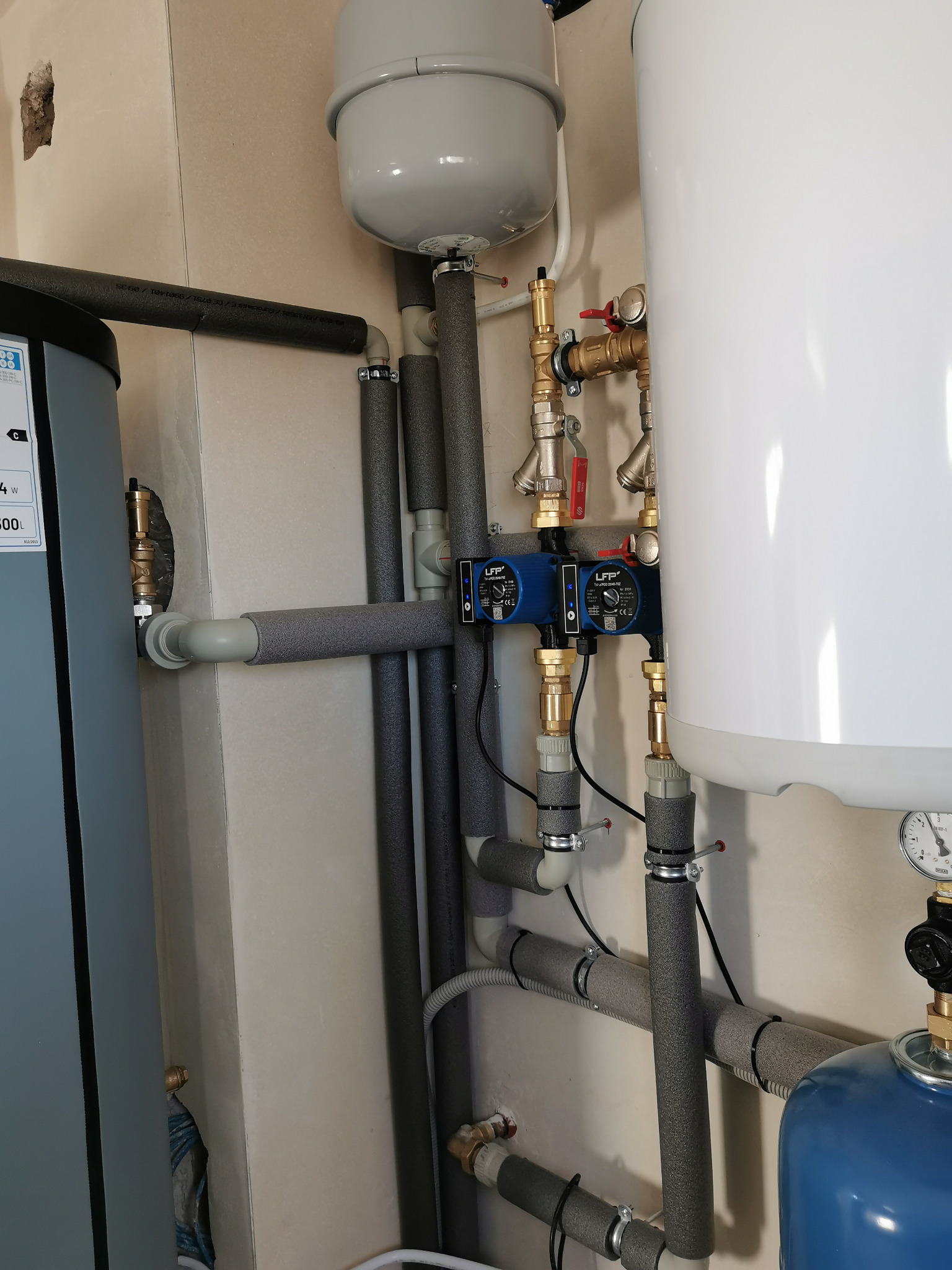 Węzeł cieplny z dwoma pompami obiegowymi LFP, zbiornikami i rurami z izolacją termiczną. Elementy instalacji grzewczej w kotłowni.