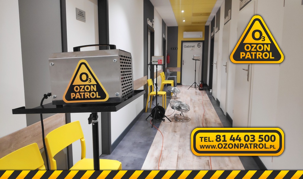 Ozonator na metalowym wózku z logo Ozon Patrol w korytarzu gabinetów, wentylatory podłogowe wspomagające proces ozonowania.