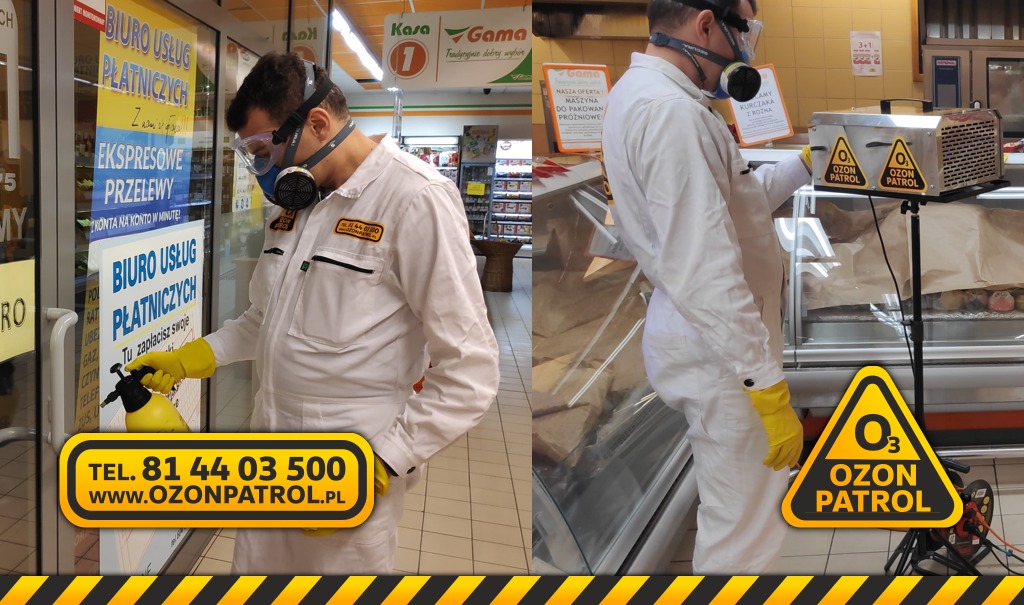 Pracownik w kombinezonie ochronnym, masce i okularach, dezynfekuje rozpylaczem szybę biura usług płatniczych. W tle widoczny ozonator z logo Ozon Patrol przy ladzie chłodniczej w sklepie.