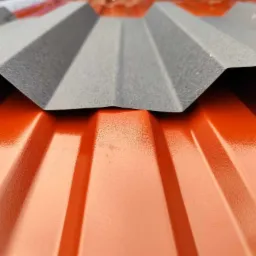 Detale łączenia blachy trapezowej w kolorach ceglastym i szarym, widoczne żłobienia i faktura materiału.