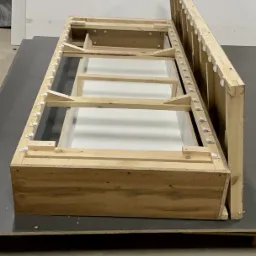 Drewniana rama sofy w trakcie montażu, widoczne elementy konstrukcyjne i mocowania.