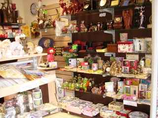 Wnętrze nowo otwartego sklepu z prezentami w Katowicach: regały z różnorodnymi artykułami dekoracyjnymi, figurkami, ramkami na zdjęcia i upominkami, oświetlone ciepłym światłem.