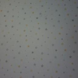 SW Projekt - Biała ściana pokryta wzorem z szarych i żółtych gwiazdek różnej wielkości.