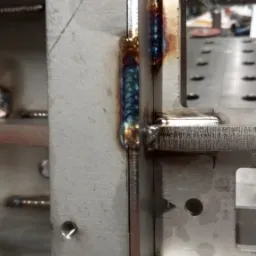 Metalowa konstrukcja spawana, widoczne spoiny o charakterystycznym zabarwieniu termicznym, precyzyjne łączenie elementów.