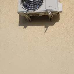 Zamontowana na elewacji zewnętrzna jednostka klimatyzacji Rotenso Versu Series z widocznymi wspornikami montażowymi i kablem zabezpieczonym opaską.