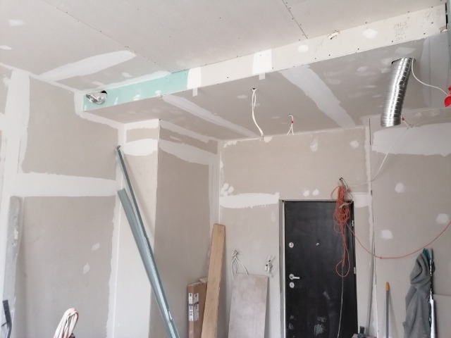 Montaż płyt karton gips na ścianach i suficie w trakcie remontu mieszkania, widoczne profile, przewody elektryczne i kanał wentylacyjny.