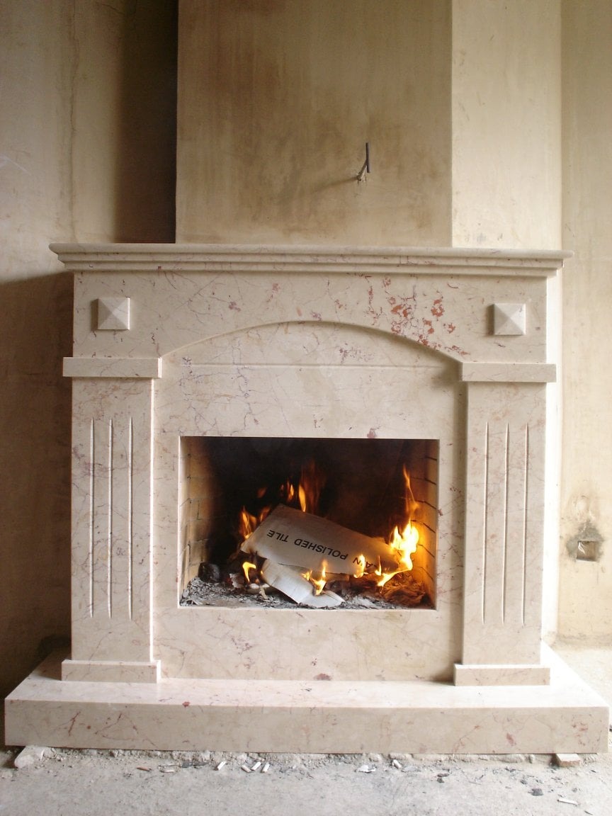 Marmurowy kominek z płomieniami palącymi kartkę z napisem 'POLISHED TILE' w surowym wnętrzu z nieotynkowanymi ścianami.