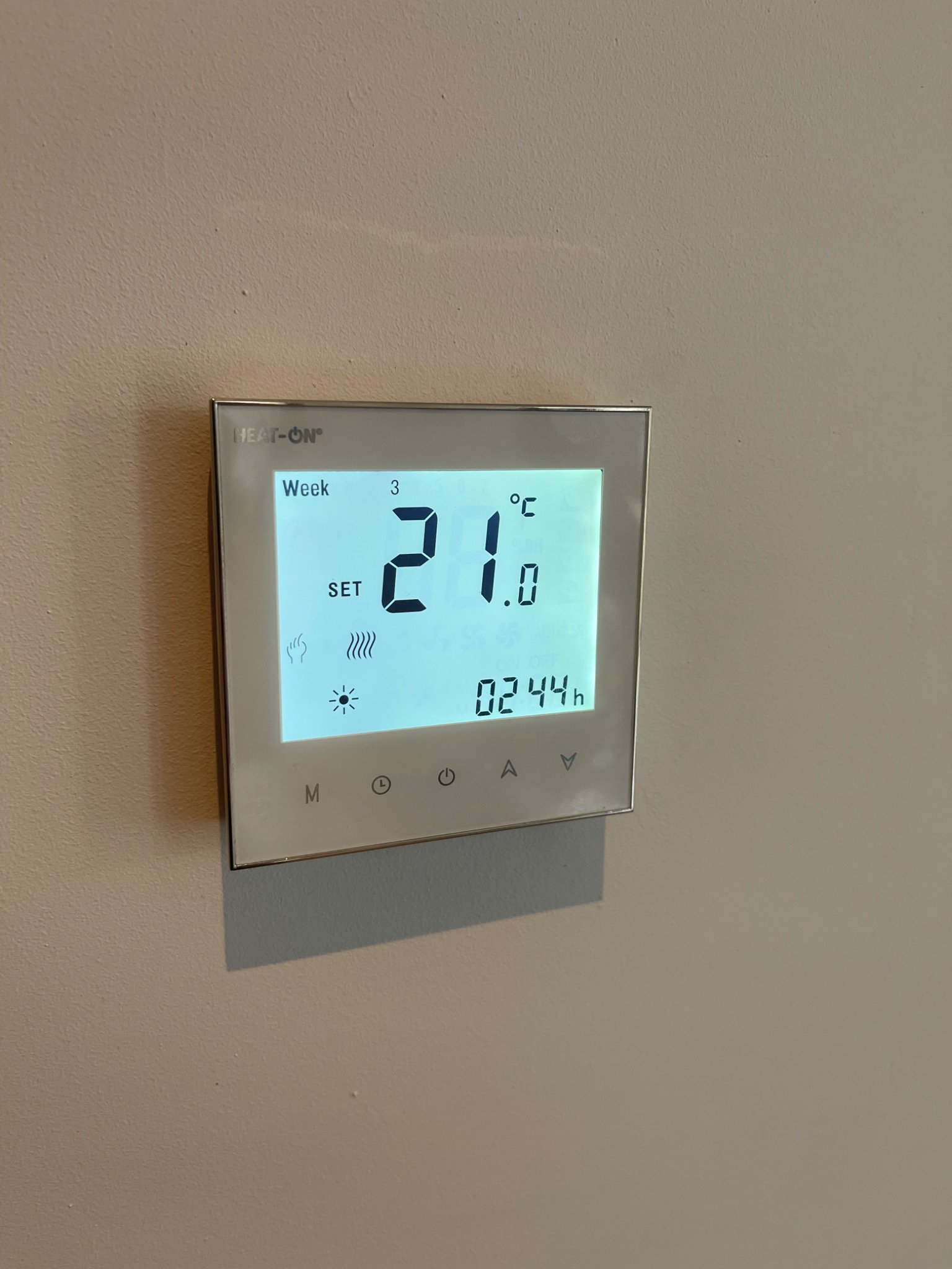 Cyfrowy termostat ścienny marki Heat-On, ustawiony na 21 stopni Celsjusza, wyświetlający trzeci tydzień i godzinę 02:44.