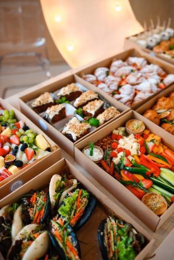 Catering w boxach: różnorodne przekąski (owoce, warzywa, ciasta, bao) w kartonowych pudełkach, elegancko ułożone, idealne na firmowe eventy.