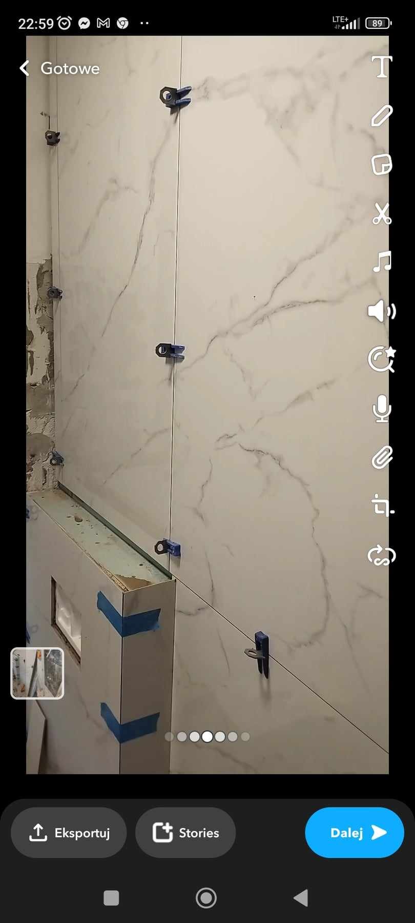 Montaż płytek imitujących marmur na ścianie w łazience, z użyciem klipsów poziomujących, widoczny fragment ściany z odsłoniętym murem.