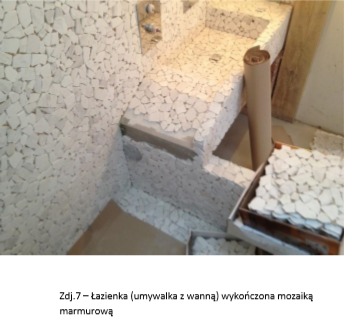 Łazienka w trakcie wykańczania mozaiką marmurową. Widoczna umywalka i wanna obłożone białymi, nieregularnymi elementami mozaiki. Część powierzchni jest jeszcze niepokryta, widać klej i przygotowane...