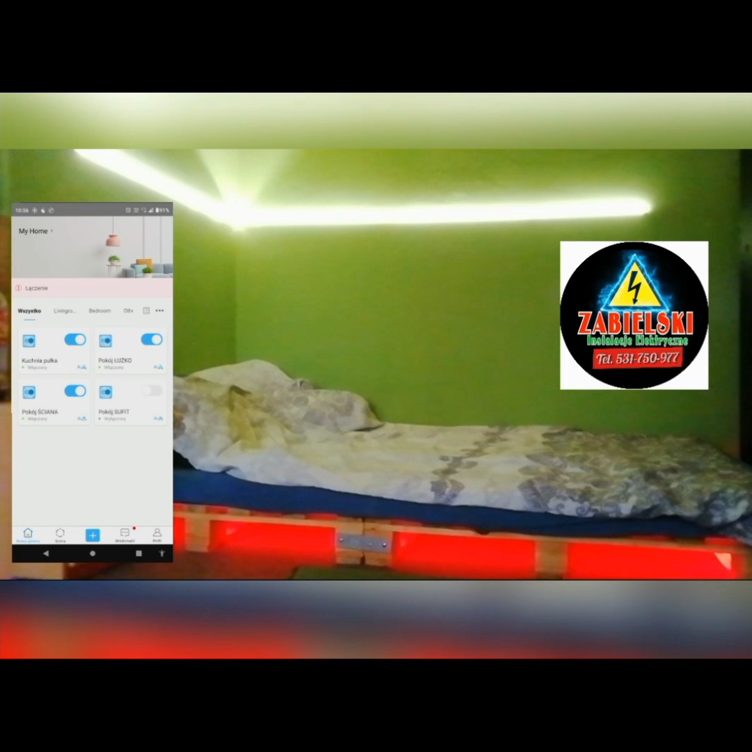 Sypialnia z oświetleniem LED: listwa na suficie i pod łóżkiem z palet, sterowanie oświetleniem widoczne na smartfonie, logo firmy elektrycznej w prawym górnym rogu.