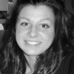 Portret uśmiechniętej kobiety z długimi włosami w czarno-białej tonacji.