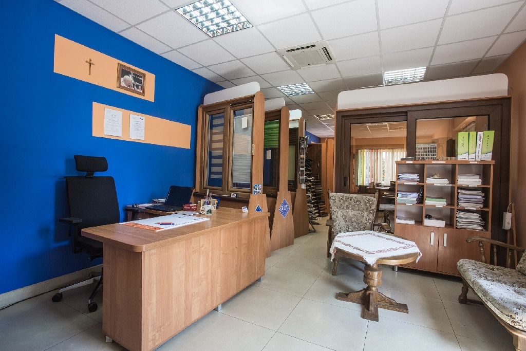 Wnętrze biura firmy Ryta&Syn z ekspozycją stolarki okiennej i drzwiowej, biurkiem, krzesłem oraz meblami biurowymi.