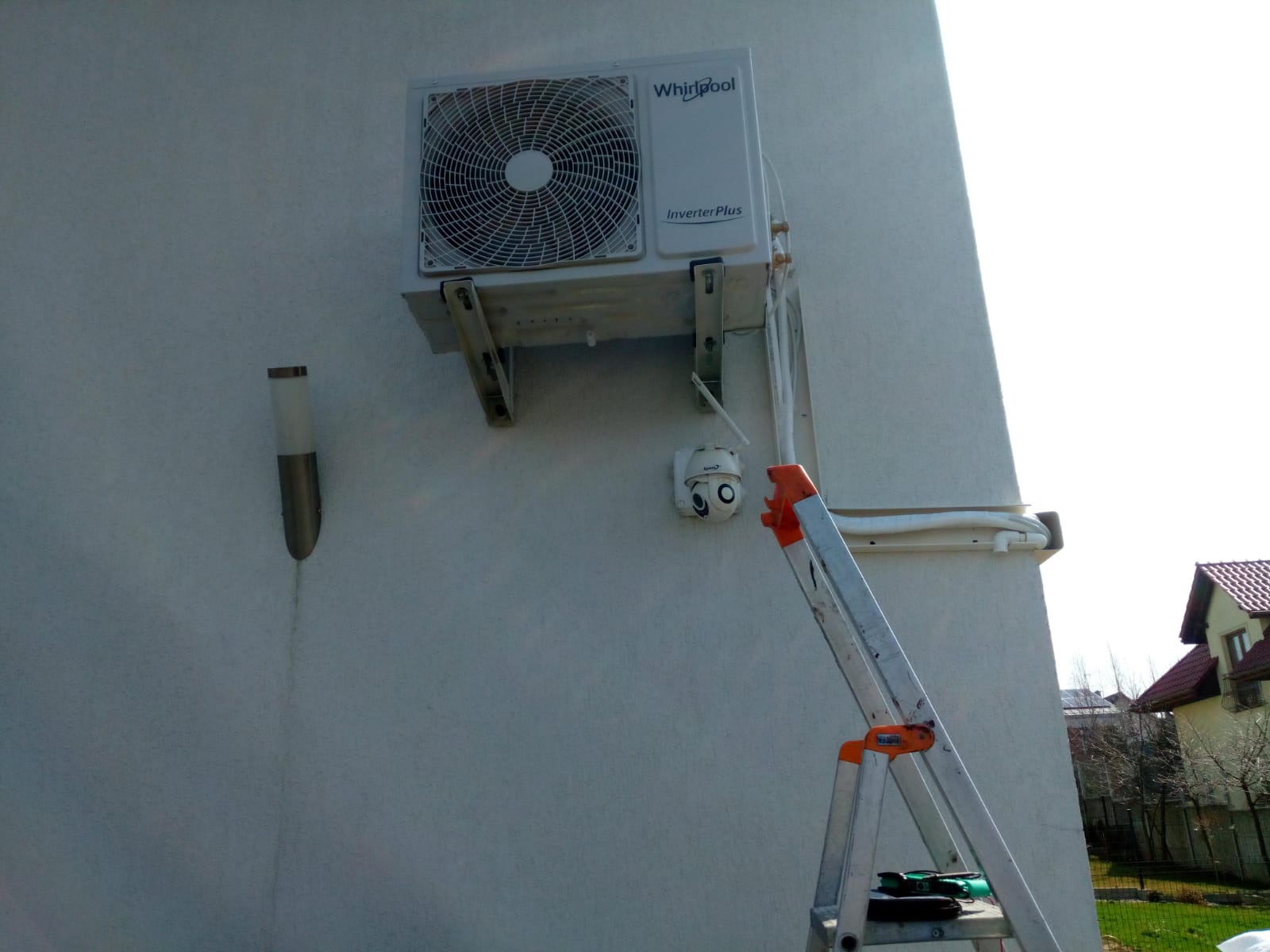 Montaż klimatyzacji Whirlpool Inverter Plus na elewacji budynku w Rzeszowie, widoczna drabina i kamera monitoringu obok jednostki zewnętrznej.