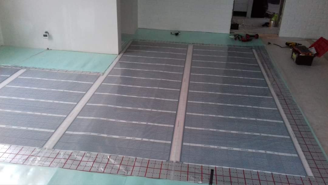 Montaż folii grzewczej pod podłogę w nowym mieszkaniu, widoczne narzędzia i materiały przygotowane do dalszych prac wykończeniowych.