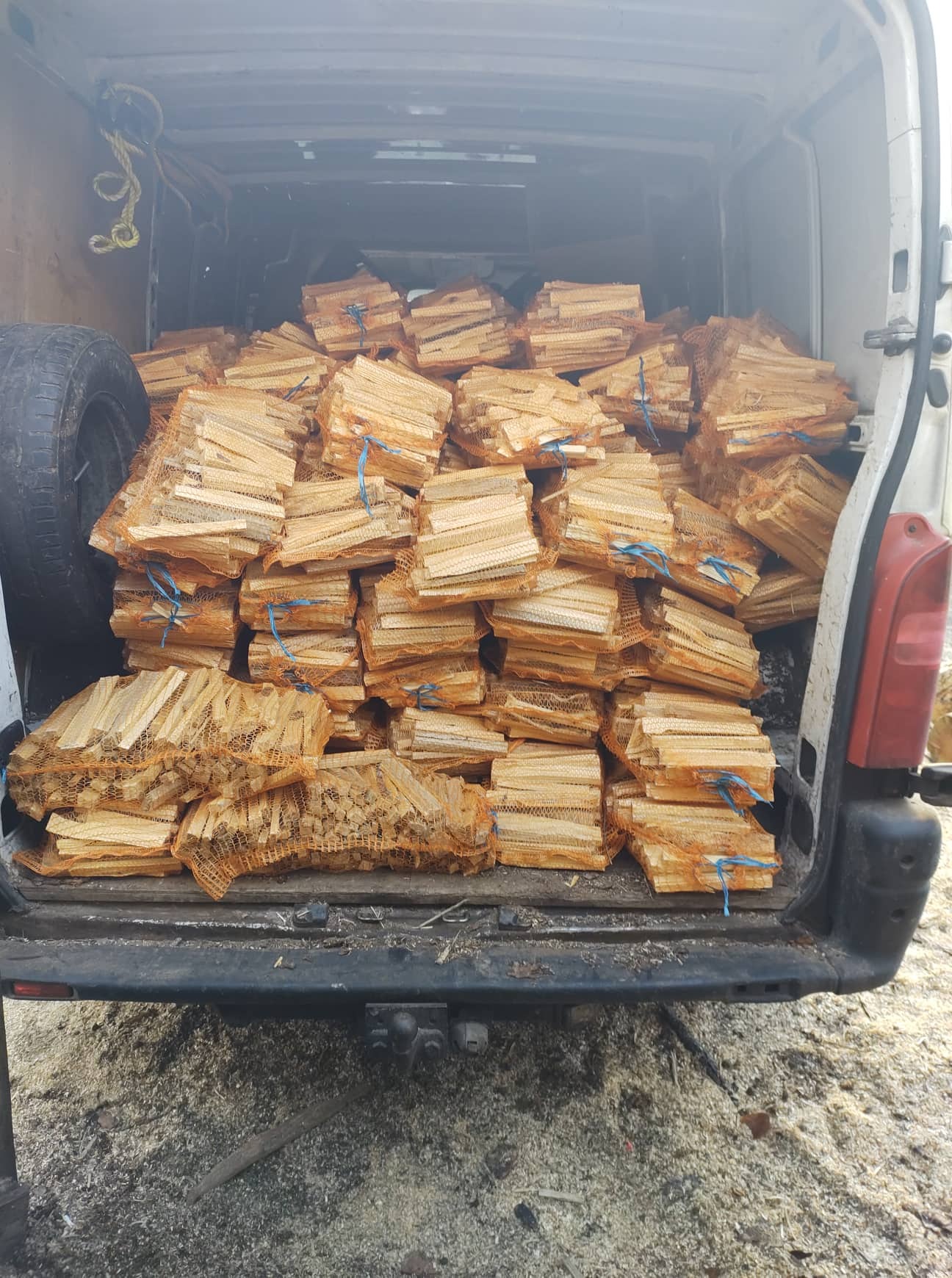 Pełny bagażnik busa w Jacinkach wypełniony workami zrąbanego drewna opałowego, gotowego do transportu i sprzedaży.