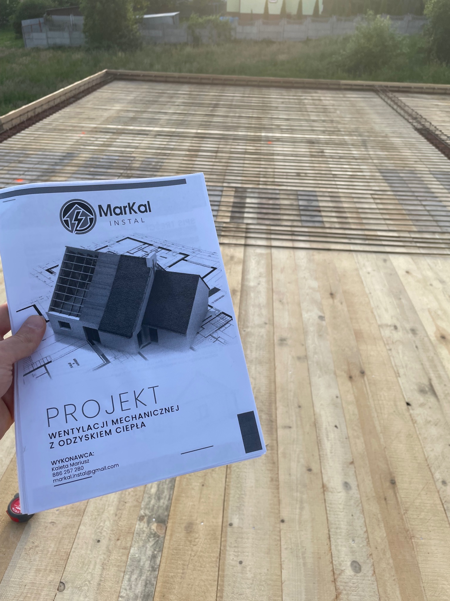 Projekt wentylacji mechanicznej z odzyskiem ciepła firmy Markal Instal prezentowany na tle drewnianej konstrukcji dachu w trakcie budowy.