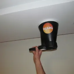 Pomiar przepływu powietrza anemometrem z nasadką pomiarową Testo przy kratce wentylacyjnej sufitowej w pomieszczeniu.