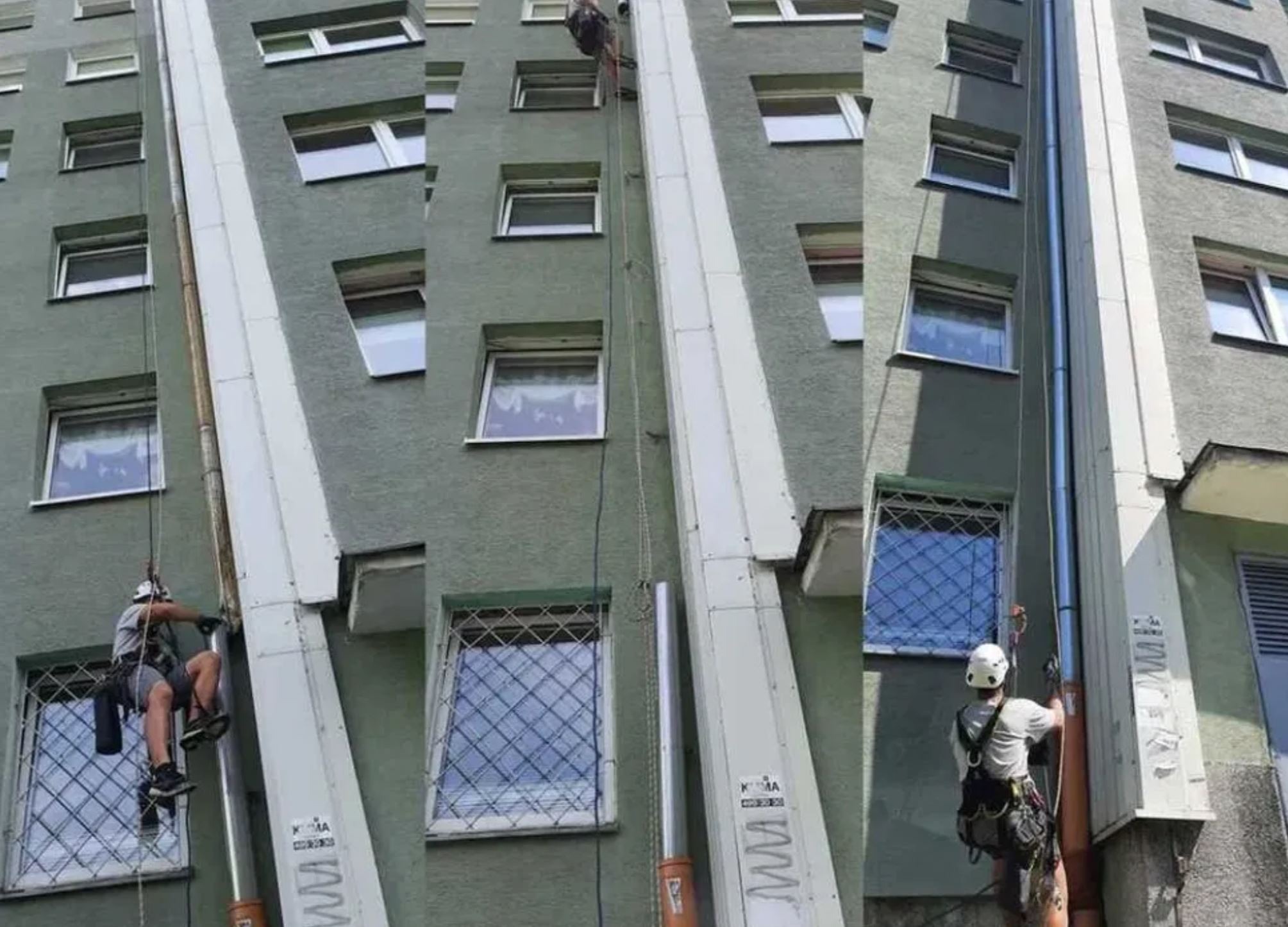 Alpinista w kasku zabezpieczony linami podczas pracy na wysokości przy elewacji budynku. Widoczne okna z kratami i fragment podnośnika.