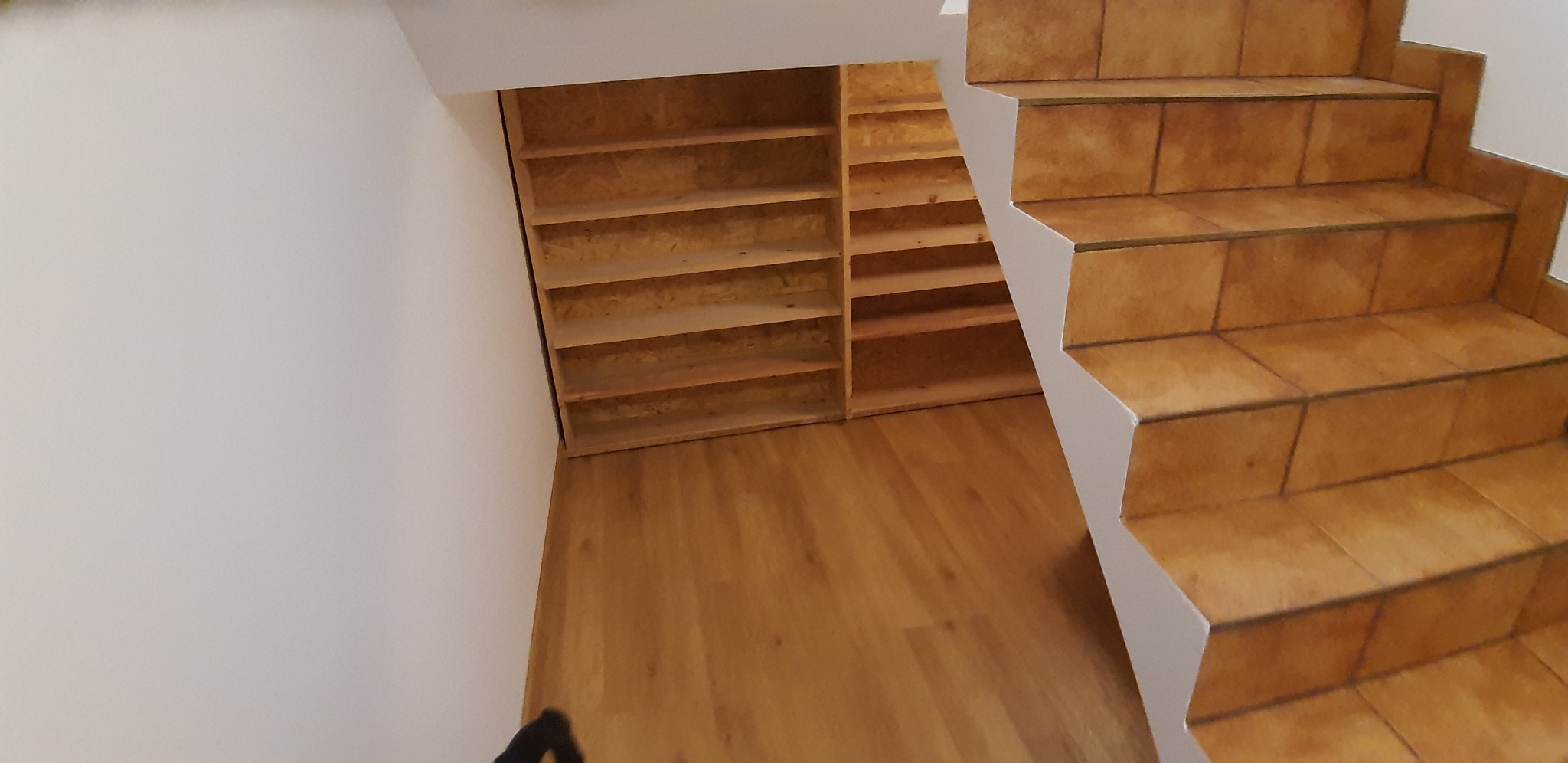 Wykończone wnętrze z drewnianą podłogą, schodami wyłożonymi terakotą i wbudowanymi półkami z płyty OSB