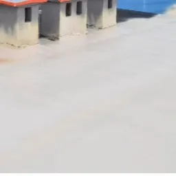 Biała pianka izolacyjna pokrywająca płaski dach z trzema kominami, widoczne ślady użytkowania na kominach.