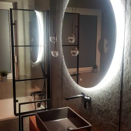 Platan construction - Nowoczesna łazienka z czarną, prostokątną umywalką nablatową, baterią w kolorze czarnym, okrągłym lustrem z podświetleniem LED i szklaną kabiną prysznicową z czarnymi profilami.