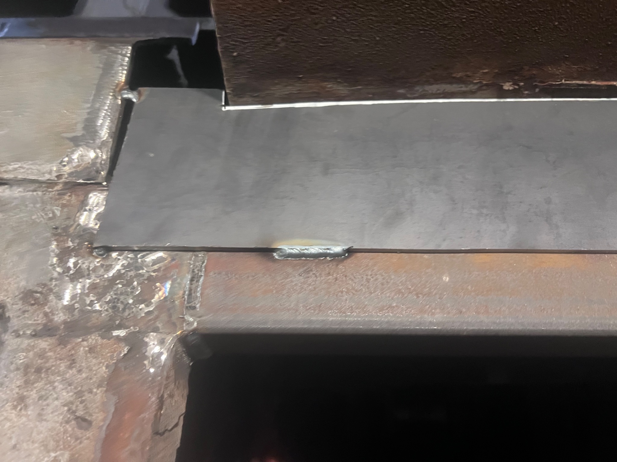 Spoina łącząca dwie metalowe płyty, widoczne odpryski i nierówności spoiny.