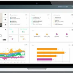 Laptop wyświetlający pulpit systemu ERP Merit z widocznymi wykresami, danymi finansowymi, listą zadań i zdjęciem pracownika, prezentujący interfejs użytkownika.