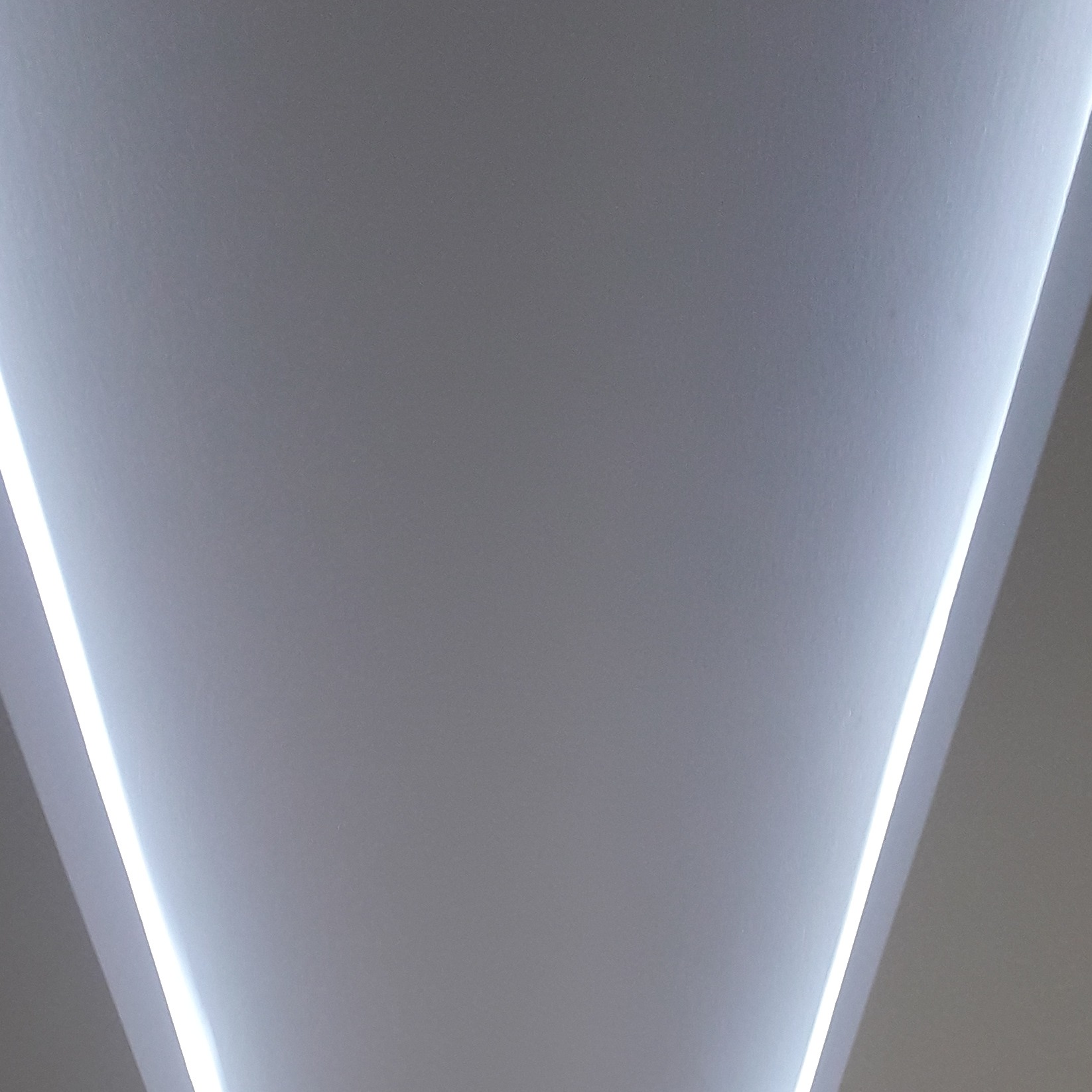 Minimalistyczne oświetlenie sufitowe z liniowymi lampami LED tworzącymi geometryczny wzór.