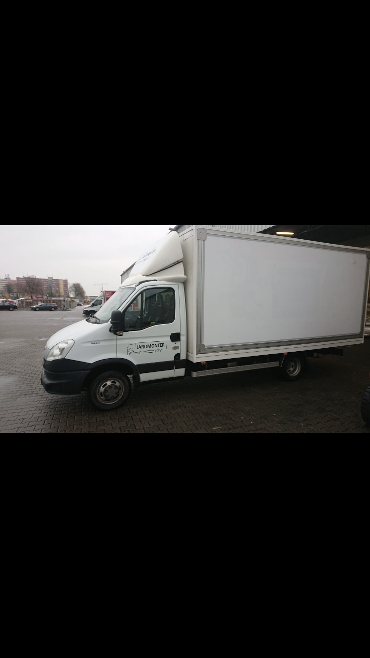 Biały samochód dostawczy marki Iveco z zabudową kontenerową, zaparkowany na mokrym bruku, z widocznym logo firmy 'Jaromonter' na kabinie.