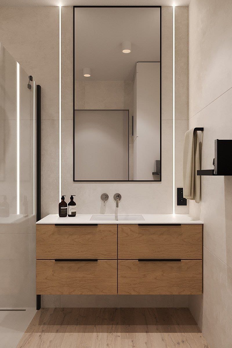 Nowoczesna łazienka we Wrocławiu: drewniana szafka pod umywalką z czarnymi uchwytami, prostokątne lustro z podświetleniem LED, jasne płytki i armatura.