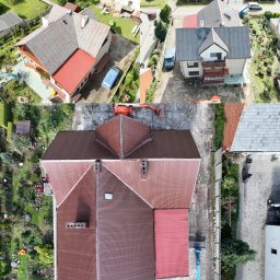 DACHY-ELEWACJE Wojciech Chomiak - Dwa domy z lotu ptaka: jeden z nowym, brązowym dachem, drugi ze starym, szarym. Widoczny podnośnik koszowy i otoczenie budynków. Ujęcie z góry.