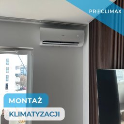 CLIMETIQA SPÓŁKA Z OGRANICZONĄ ODPOWIEDZIALNOŚCIĄ - Zamontowana, biała klimatyzacja Haier na szarej ścianie w nowoczesnym wnętrzu. Widoczne drewniane panele dekoracyjne i okno z widokiem na miasto.