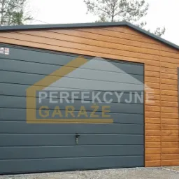 Gotowy garaż blaszany z drewnopodobną elewacją i antracytowymi drzwiami segmentowymi oraz drzwiami wejściowymi, widoczne drzewa w tle.