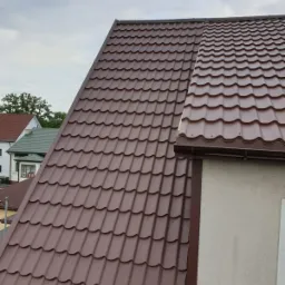 Brązowy dach z blachodachówki modułowej, widok z góry, z zamontowanym systemem rynnowym w kolorze dachu.