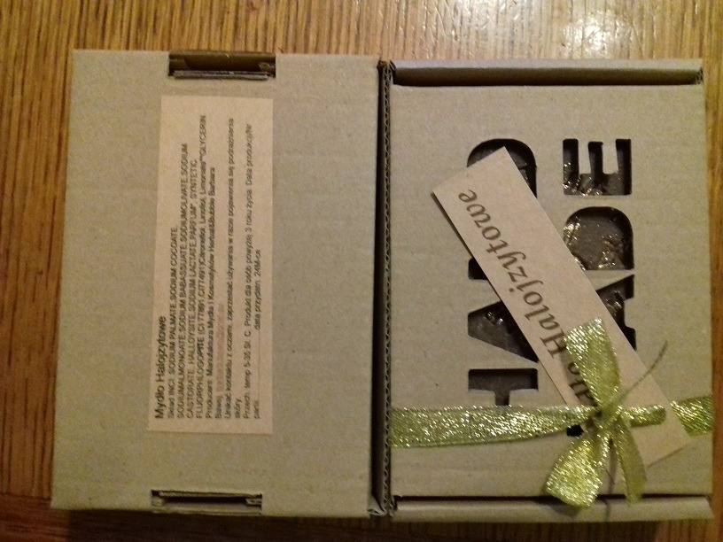 Otwarty kartonik z mydłem halojzytowym, widoczna etykieta ze składem i ozdobna wstążka z kokardką.