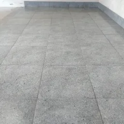 Szare, granitowe płytki podłogowe ułożone w kwadraty z szarą listwą przypodłogową w Gorlicach, widok z perspektywy podłogi.