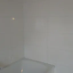 Białe, błyszczące płytki ścienne ułożone w łazience, widoczna wanna i fragment drewnianego taboretu, sufit z widocznymi śladami prac wykończeniowych.